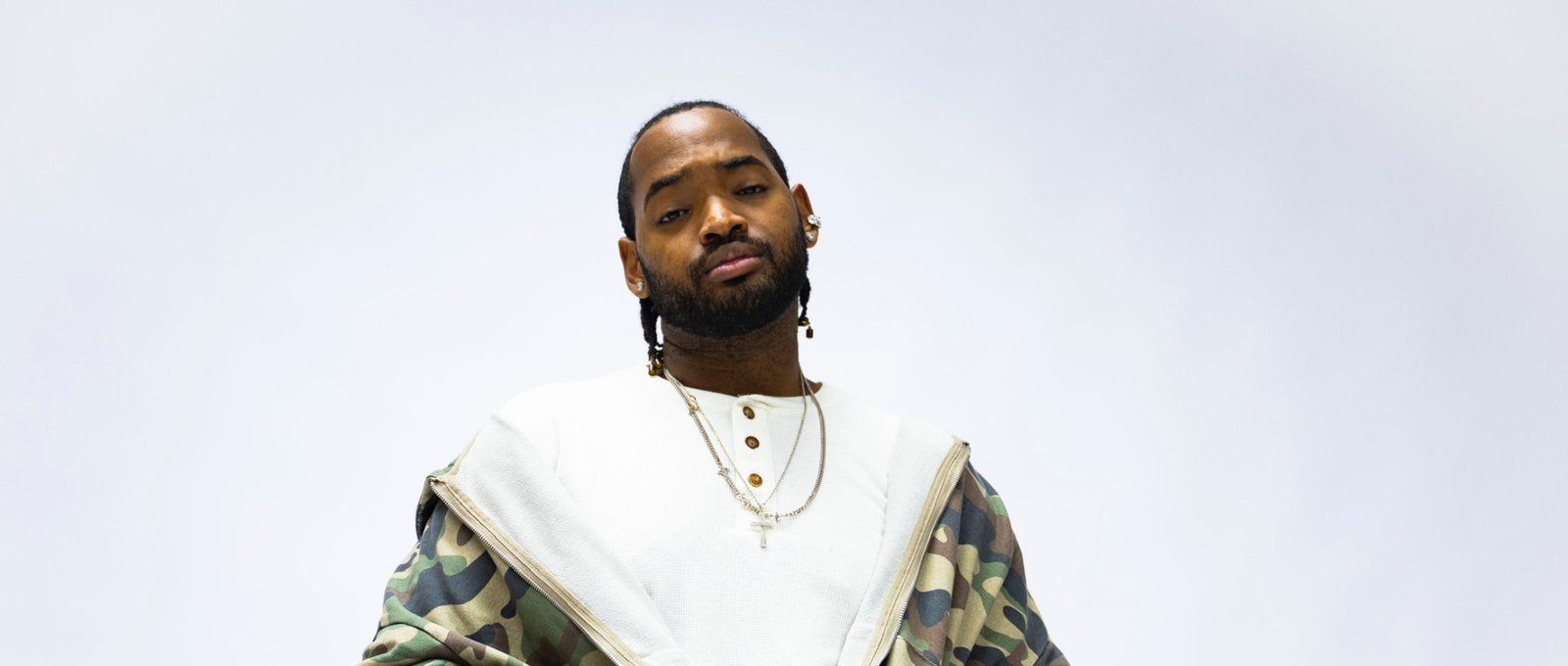 RaSean Parks in a camo zip jacket, hands in the pockets, looking down at the camera